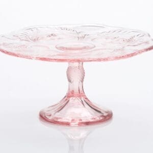 Elegant pink glass cake stand with decorative etching.