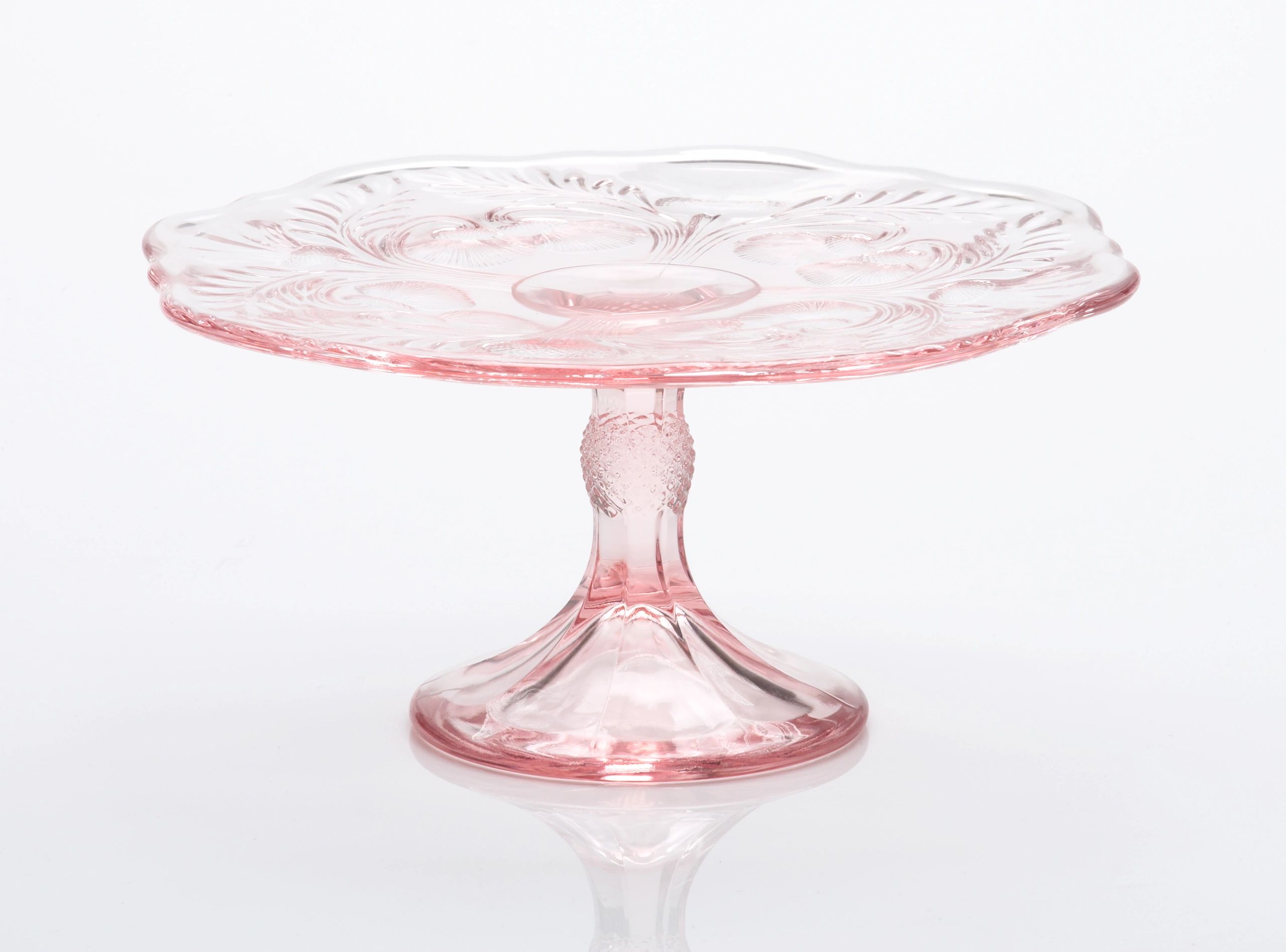 Elegant pink glass cake stand with decorative etching.