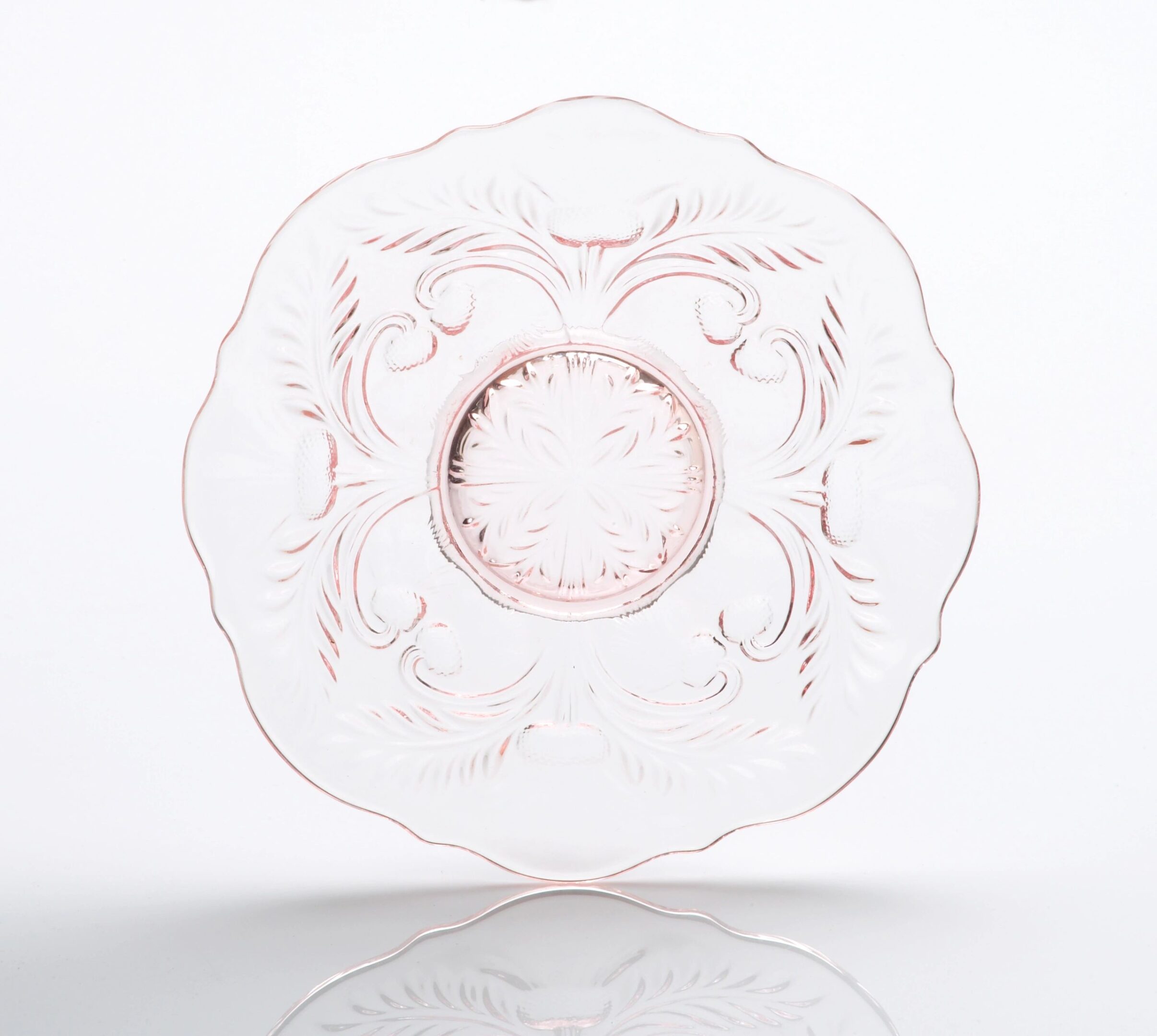 Transparent glass plate with intricate floral etching and scalloped edges.