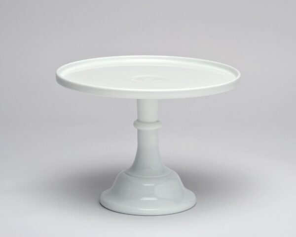 A white ceramic cake stand with a wide, flat top and sturdy pedestal base.