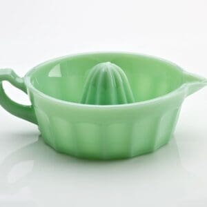 Green ceramic citrus juicer with handle and spout.