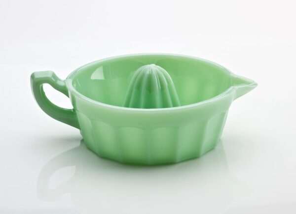 Green ceramic citrus juicer with handle and spout.