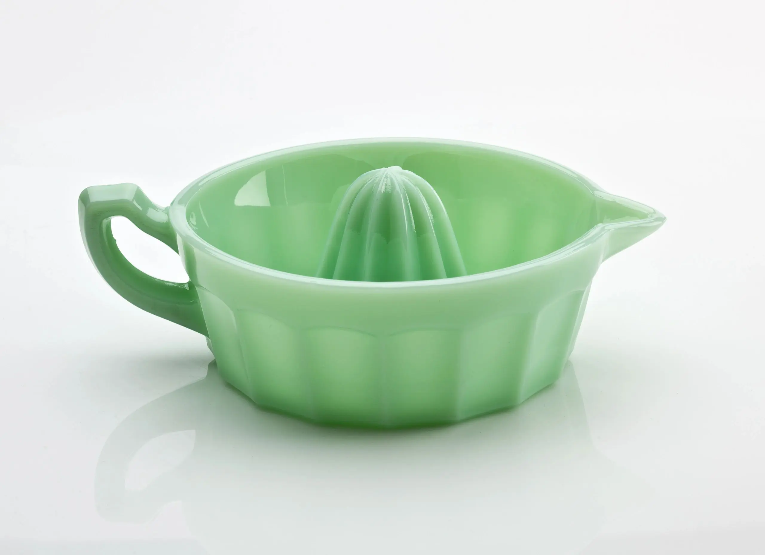 Green ceramic citrus juicer with handle and spout.