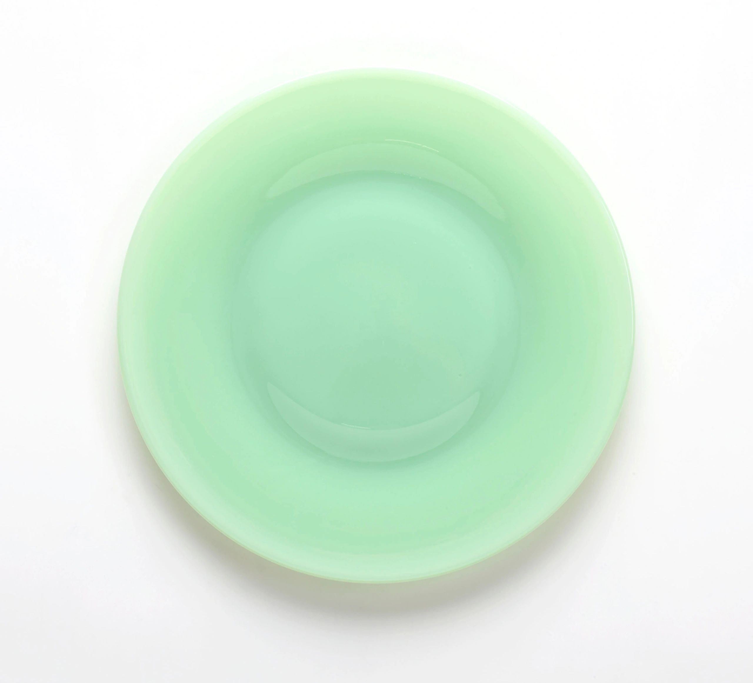 A round, mint-green plate with a smooth, glossy surface.