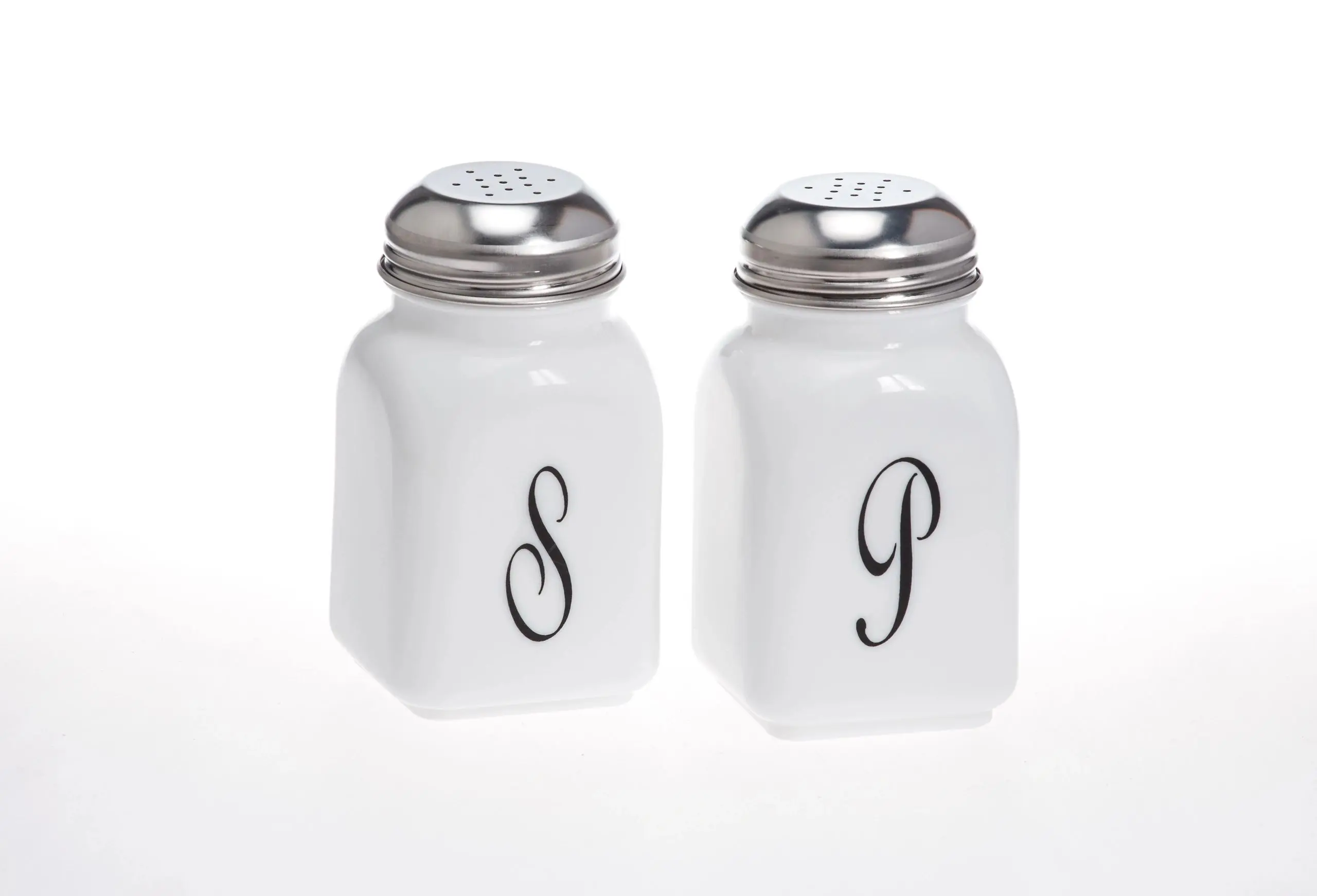 White ceramic salt and pepper shakers with silver tops and initials S and P.