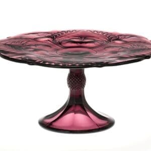 A purple glass pedestal cake stand with intricate design.