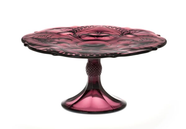 A purple glass pedestal cake stand with intricate design.