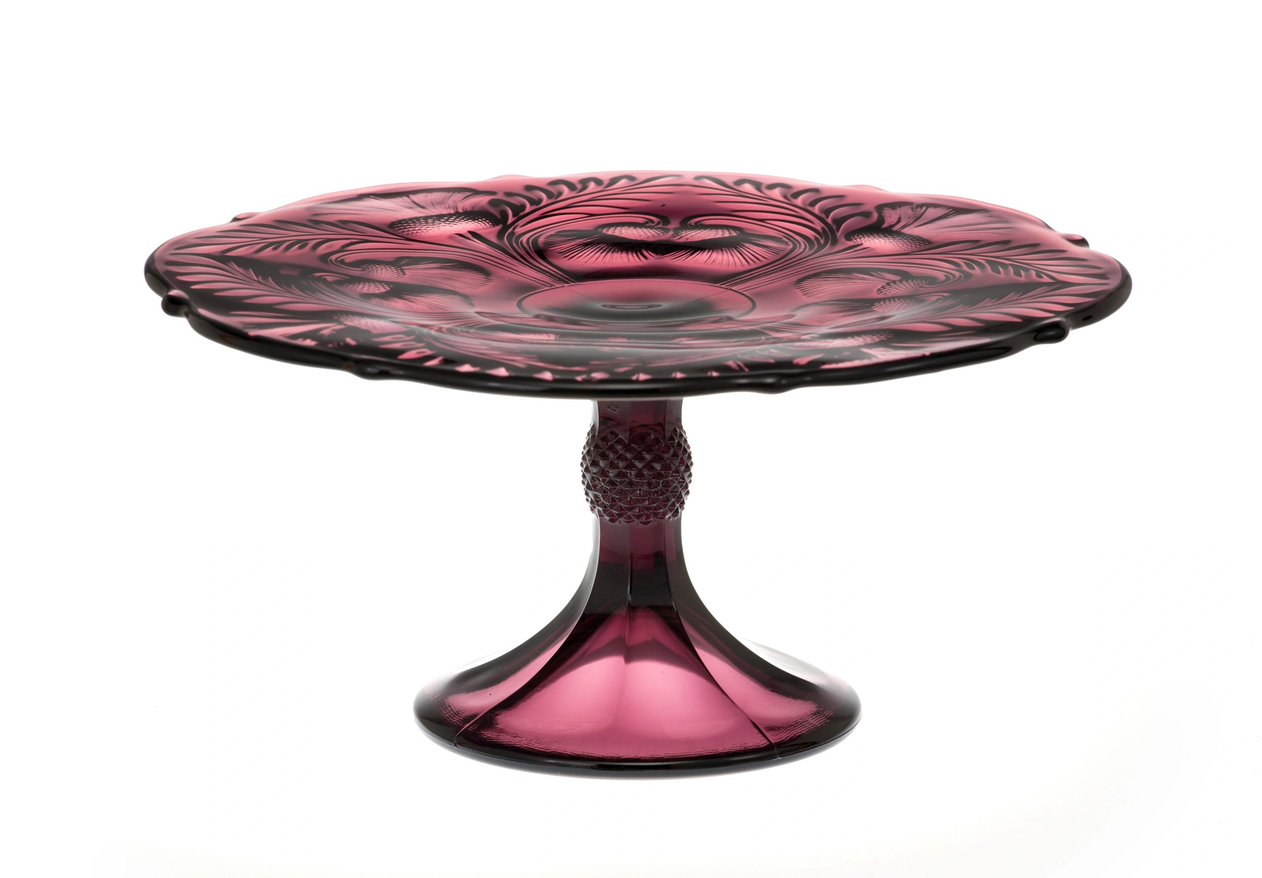 A purple glass pedestal cake stand with intricate design.