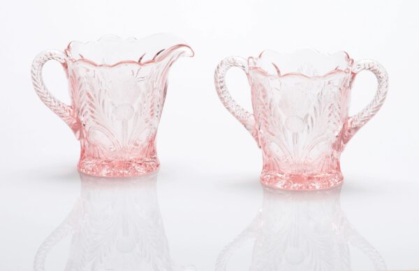 Delicate pink glass creamer and sugar bowl with floral patterns.