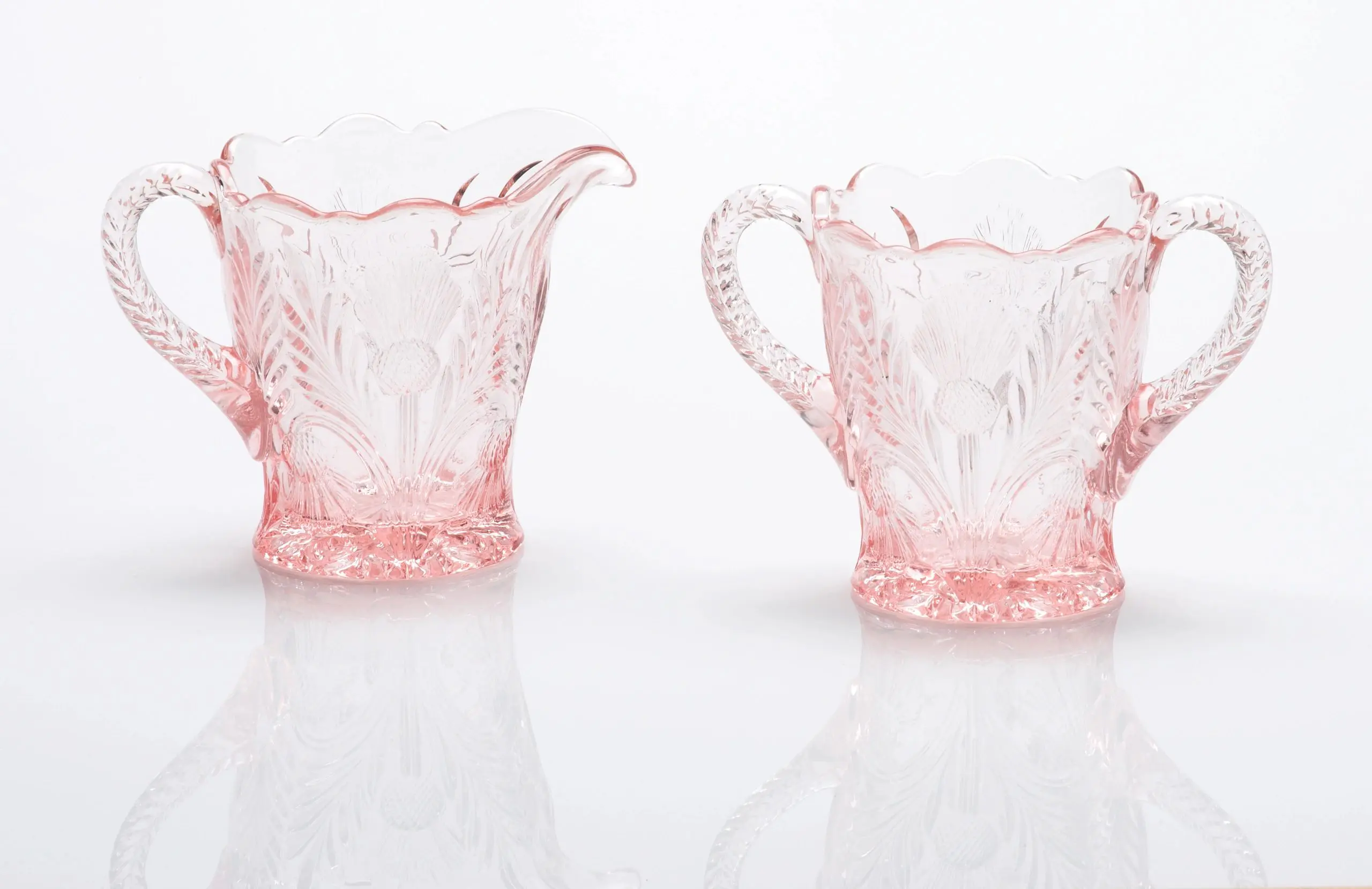 Delicate pink glass creamer and sugar bowl with floral patterns.