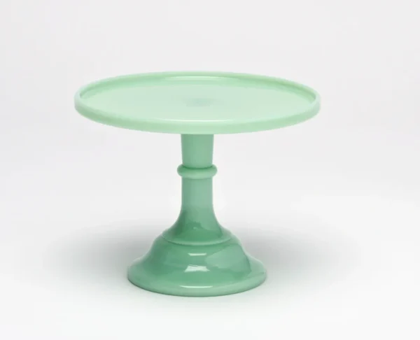 A pastel green ceramic cake stand with a wide base and round top.