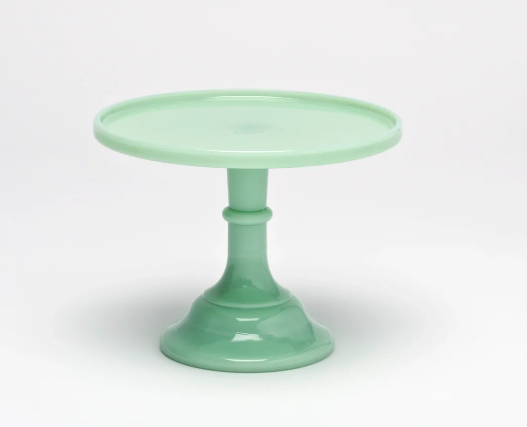 A pastel green ceramic cake stand with a wide base and round top.