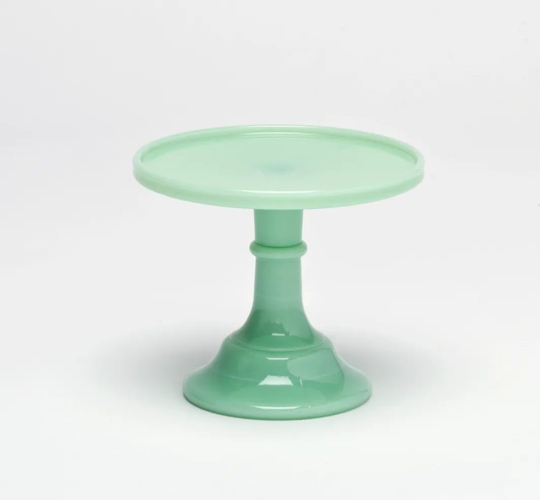 A mint green cake stand with a wide base and flat top.